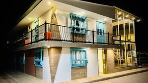 A two-story building with a balcony, large windows, and a brick facade. - CLUB EL LLANO (Cómbita)