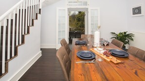 A dining area with a wooden table set for four, surrounded by brown upholstered chairs. A staircase with white railings is visible to the left. - River View House Cleveland Bridge (Bath)