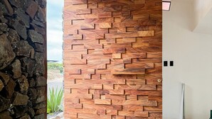 Un interior moderno con pared de piedra, panel de madera y suelo de hormigón con felpudo.