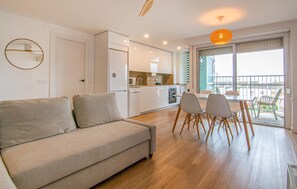Een modern appartement met een bank, eettafel, stoelen, een keuken en een balkon met uitzicht.