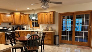 A kitchen with wooden cabinets, a dining table with chairs, a ceiling fan, and a view through glass doors. - RENEWING LICENSE: TEMPORARILY NO VACANCY- DO NOT AUTO BOOK3 BR Rambler Home - (Honesdale)