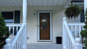 A front porch with a wooden door, white railings, and a hanging plant. - RENEWING LICENSE: TEMPORARILY NO VACANCY- DO NOT AUTO BOOK3 BR Rambler Home - (Honesdale)