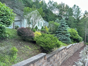 Set amidst lush gardens and a rustic stone wall, this serene home offers a peaceful retreat.