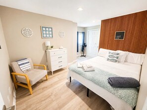 A bedroom with a bed, a chair, a dresser, and a wall with a sign. - Lake Front - Kayaks - Hot Tub - Sleeps 8 (Akron)