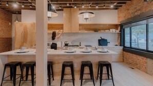 A modern kitchen with a central island, wooden cabinets, and black bar stools. - The Timberline (Leadville)
