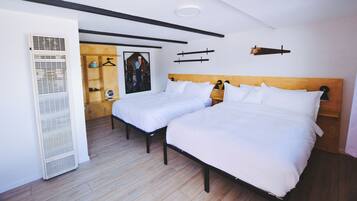 A room with two beds, a wooden headboard, a white radiator, and a framed picture on the wall.