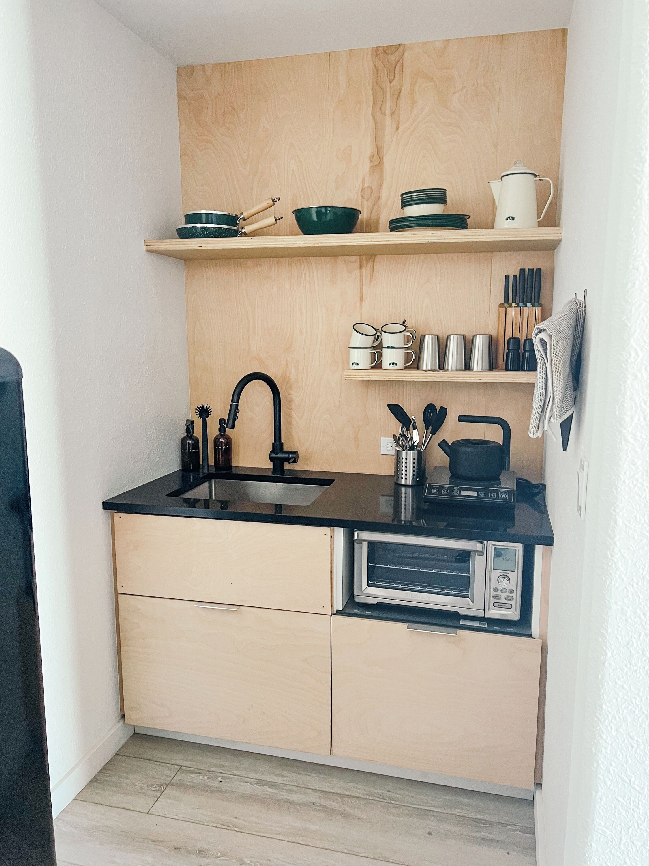 Een kleine keuken met een zwart aanrecht, een ingebouwde oven en houten kastjes.