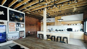 A modern kitchen with a brick wall, wooden ceiling beams, and a bar area with stools. - The Timberline (Leadville)