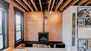 A room with exposed wooden beams, a brick wall, a fireplace, and a sofa. - The Timberline (Leadville)