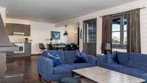Una sala de estar moderna con dos sofás azules, una mesa de centro y una zona de comedor con mesa y sillas.