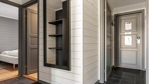 Un pasillo con un mueble negro empotrado, una puerta con mirilla y suelo de baldosas.