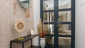 A modern interior with a textured wall, a console table with decorative items, and a large glass door.