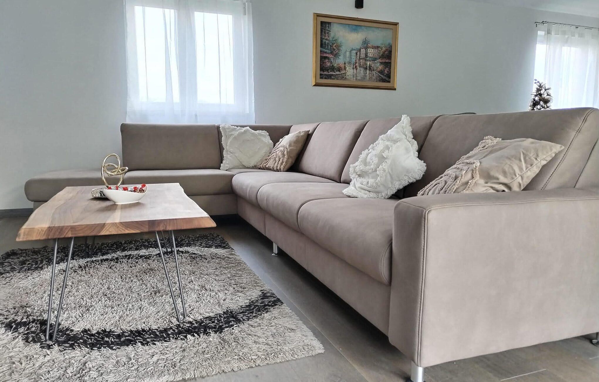 Een woonkamer met een beige bank, een houten salontafel en een zwart-wit vloerkleed.