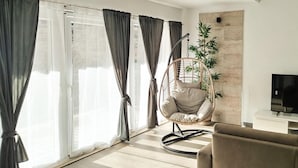 A living room with a hanging chair, a sofa, and a TV.