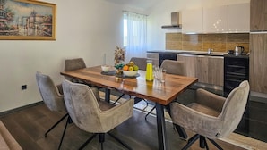 A modern dining area with a wooden table, cushioned chairs, and a painting on the wall.