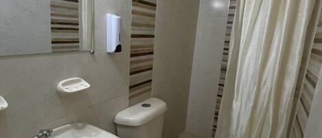 A compact bathroom with a sink, toilet, and shower curtain.