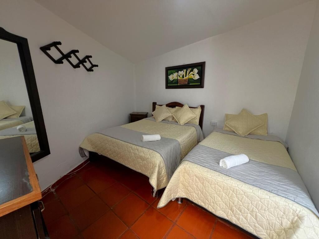 A bedroom with two beds, a mirror, and a painting on the wall.