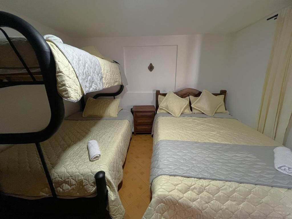 A room with two beds, each with a headboard and pillows, and a small wooden nightstand between them.