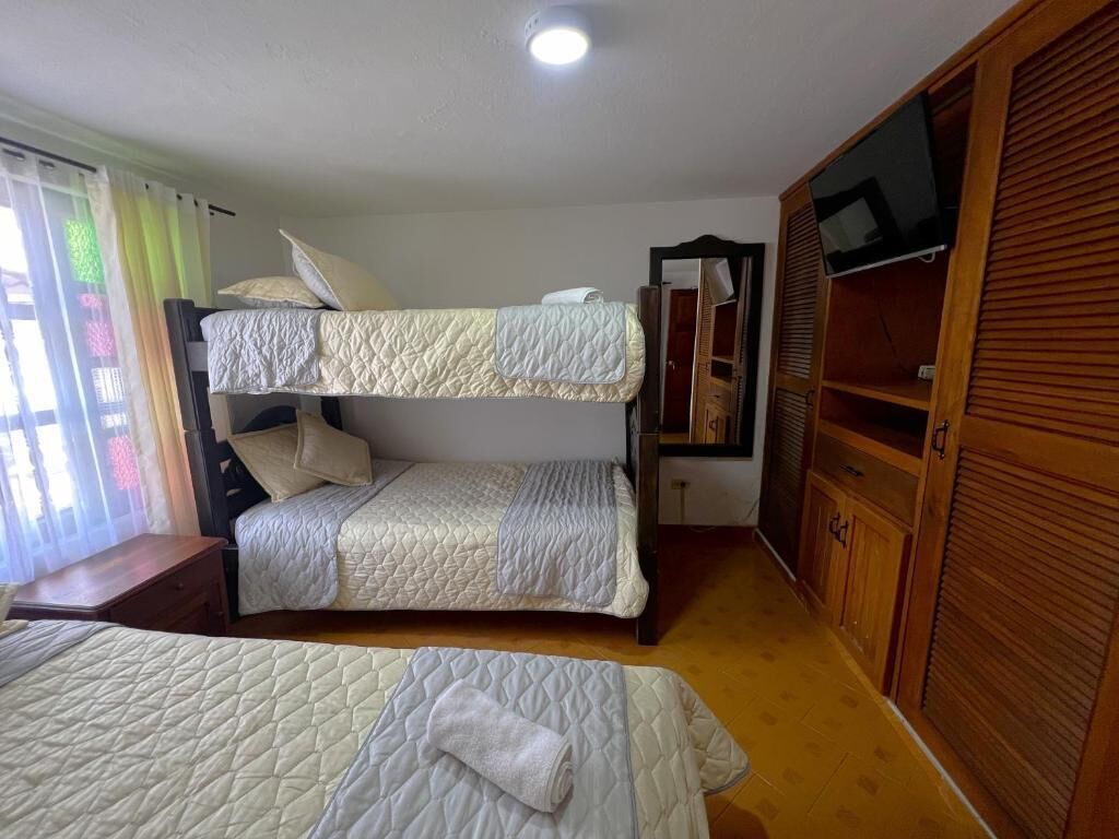 A room with two bunk beds, a wooden wardrobe, and a television.