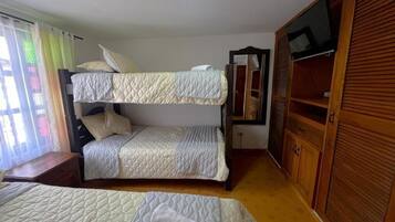 A room with two bunk beds, a wooden wardrobe, and a television.