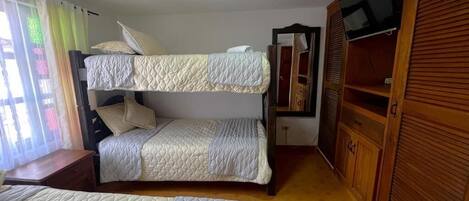 Una habitación con dos literas, un armario de madera y una televisión.