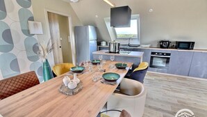 Una cocina moderna con una isla central, un comedor con mesa de madera y vistas al exterior.