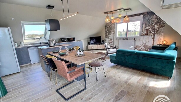 Una cocina moderna con comedor, un sofá color turquesa y un amplio ventanal.