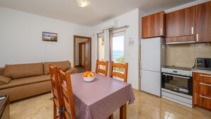 A compact living space with a kitchenette, a dining area with a table and chairs, a sofa, and a view through a door.