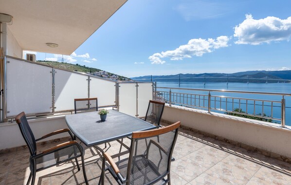 Enjoy a serene view of the bridge over the water from this balcony, complete with a table and four chairs.