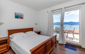 Relax in this serene room with a large bed, balcony offering sea and mountain views, and a cozy seating area.