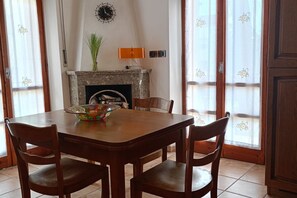 A dining area with a wooden table and chairs, a fireplace, and a window with curtains. - SE069 - Senigallia, large four-room apartment convenient to services (Senigallia)