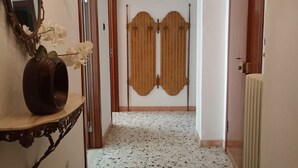 A hallway with a white speckled floor, a mirror, a vase with flowers, and a wooden door with a decorative panel. - SE069 - Senigallia, large four-room apartment convenient to services (Senigallia)