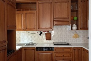 Een keuken met houten kastjes, een vaatwasser en een betegelde spatwand.
