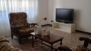 A living room with a sofa, a chair, a coffee table, a TV on a stand, and a vase with a rose. - SE069 - Senigallia, large four-room apartment convenient to services (Senigallia)