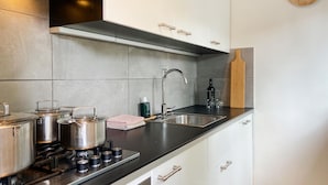 A modern kitchen with stainless steel appliances, a black countertop, and white cabinetry.