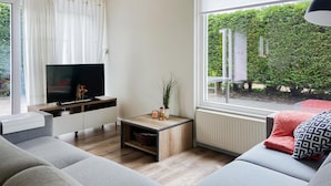 A modern living room with a sofa, TV, and a small table with decorative items.