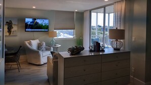 Una sala de estar moderna con un ventanal grande, un televisor de pantalla plana, una zona de comedor y una distribución de asientos acogedora.