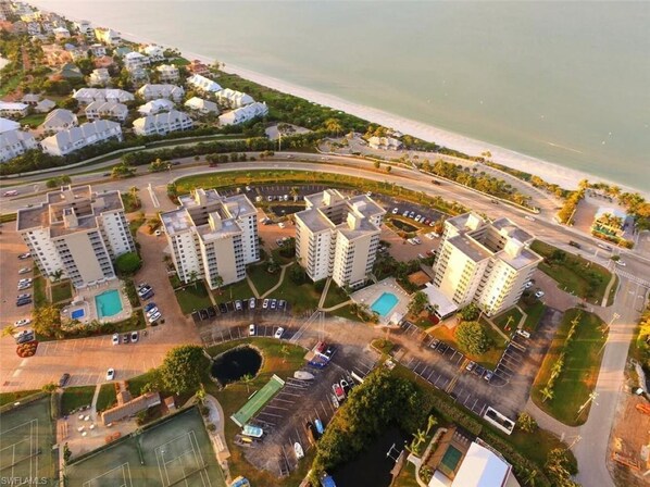An aerial view of a coastal residential area with multiple high-rise buildings, a marina, and a beach.