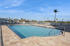 Relax by the pool surrounded by lush palm trees.