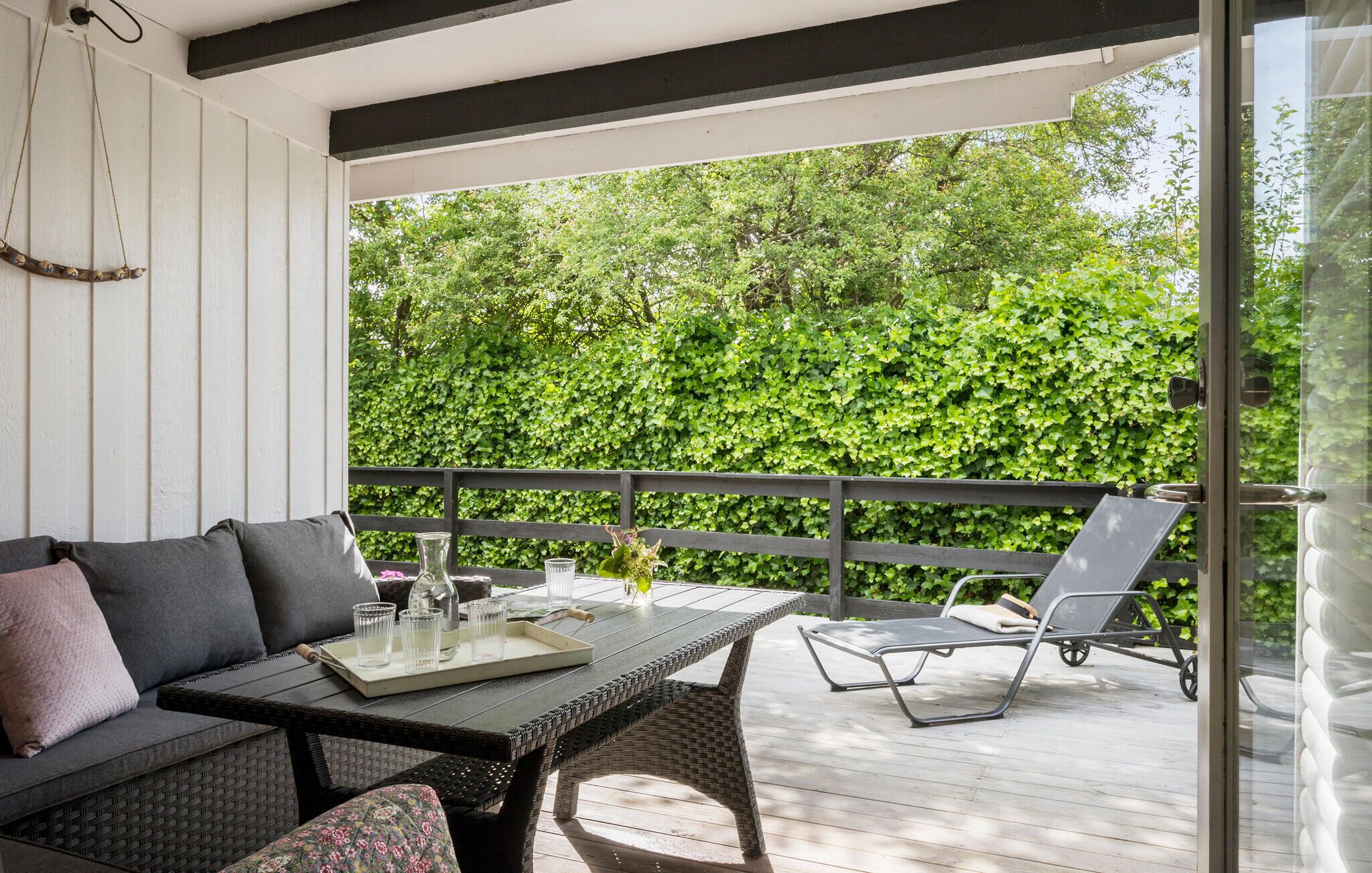 A covered outdoor seating area with a table, chairs, and a sofa.
