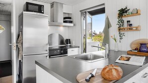 Eine moderne Küche mit Edelstahlgeräten, einem großen Fenster und einem Holzerntisch mit einem Messer.