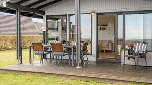 Eine moderne Außenpatio mit Essbereich, einer Couch und einem Sessel.