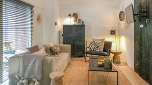 Un salon chaleureux avec un canapé, un fauteuil et une table basse, agrémenté d’un meuble rustique et d’objets décoratifs.