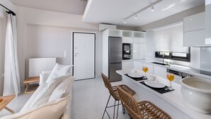 Een moderne keuken met witte kasten, een inbouwoven en een eethoek met een tafel en stoelen.