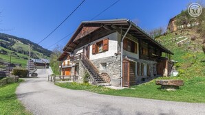 Una casa de piedra tradicional con una escalera de madera que conduce a la entrada, rodeada de un paisaje rural.