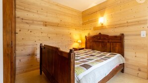 Un dormitorio con paneles de madera, una cama de madera, una mesita de noche con lámpara y una lámpara de pared.