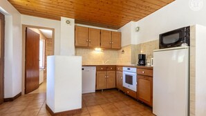 Una cocina con armarios de madera, microondas, lavavajillas y cafetera.