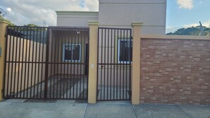 A gated residential area with a brick wall and a beige building. - Casa de Vacaciones (La ceiba)