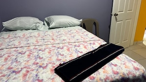 A bed with a floral bedspread, pillows, and a black object on it. - Casa de Vacaciones (La ceiba)