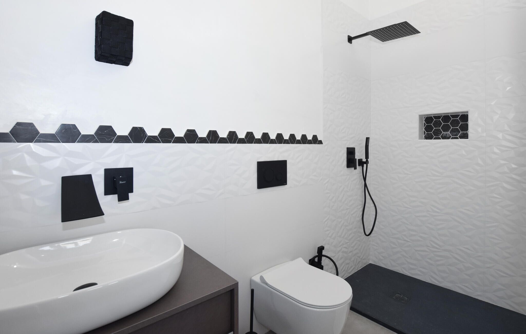 A modern bathroom with a white sink, toilet, and shower area.